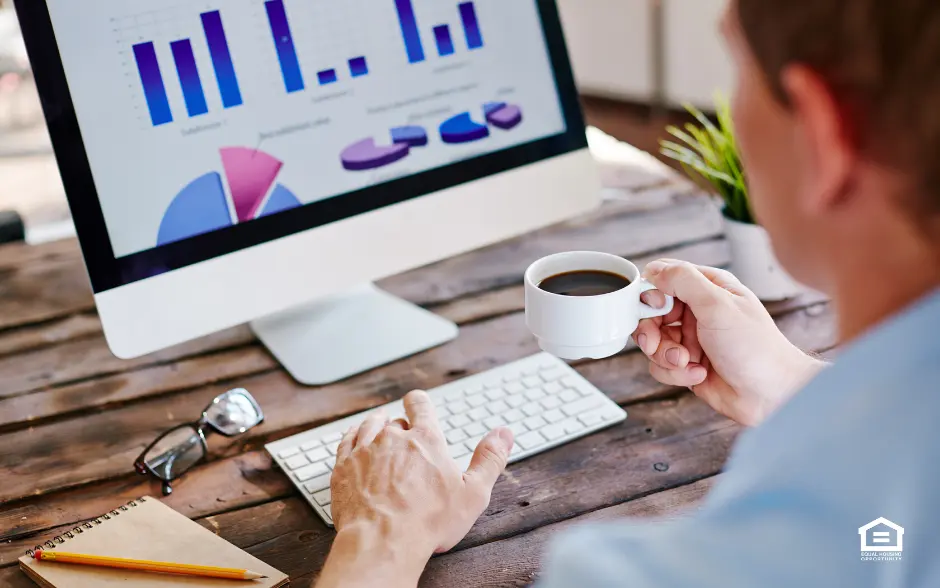 Man looking at real estate market graphs on a computer screen