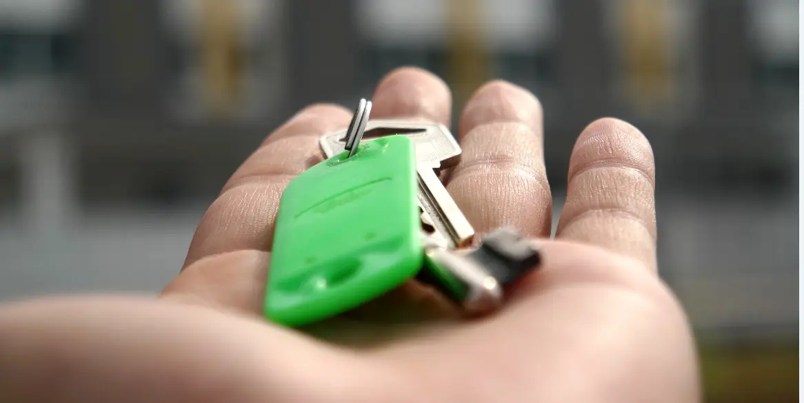 Hand holding keys in front of house