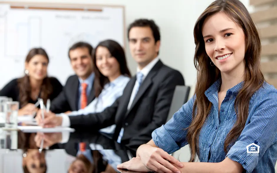 Business meeting with woman in foreground smiling.