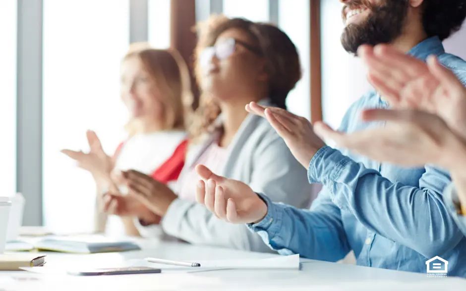 People sitting at table during real estate conference clapping hands