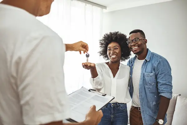 Smiling black couple being handed keys to home.