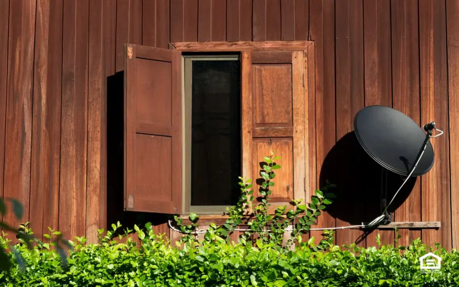 Small satellite dish on side of house next to a window