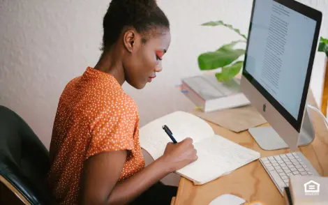 Woman writing in notebook at desk.