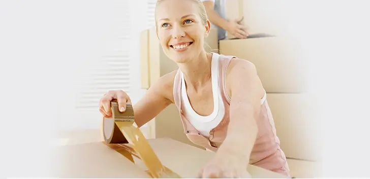 Woman Smiling While Taping a Moving Box